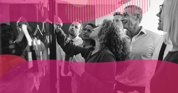 Team in a meeting analyzing post-its on a board during strategic marketing planning.