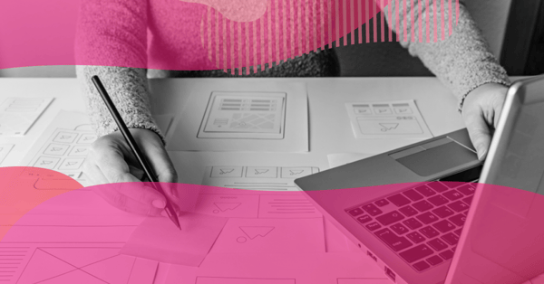 Person writing on a sticky note while reviewing printed wireframes of screens next to a laptop, representing interface and copy planning in UX writing.