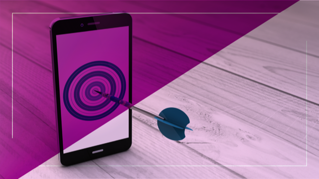 Celular com alvo na tela sendo atingido por um dardo, simbolizando precisão nas estratégias de mobile marketing.
