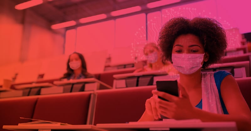 Estudante usando máscara em sala de aula enquanto mexe no celular, representando os desafios da retenção escolar durante a pandemia.
