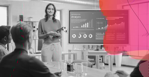 A woman presents data science graphs and reports at a corporate meeting, highlighting practical insights for marketing strategies.