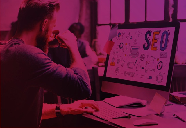 Man sitting in front of a computer with the word "SEO" on the screen, symbolizing the analysis and monitoring of performance indicators in search engine optimization strategies.