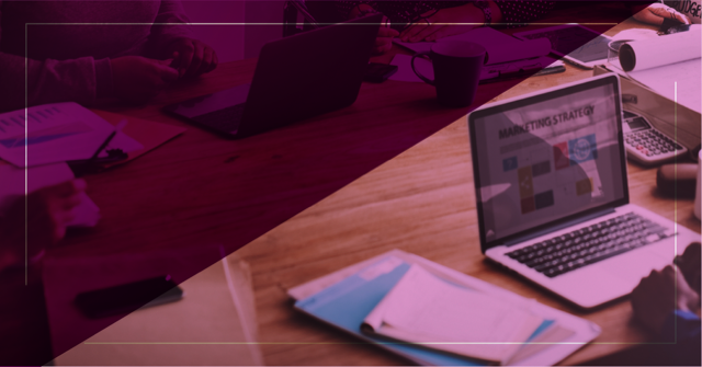 Image of a meeting table with notebooks, documents and professionals analyzing a screen with the word “Marketing Strategy”, suggesting collaborative planning and data-driven decisions.