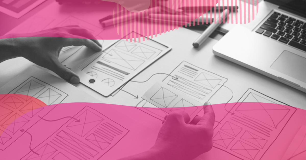 Hands arranging screen wireframes on a desk next to a laptop, representing the UX design process for digital interfaces.
