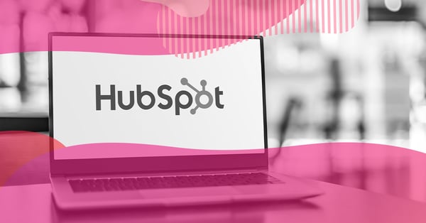 Notebook aberto exibindo o logo da HubSpot na tela, com sobreposição rosa, representando a plataforma de CRM utilizada por clientes Hubspot.