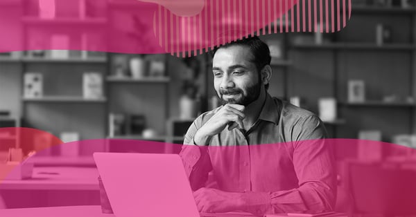 Profissional sorridente usando notebook em um escritório enquanto faz curso online da HubSpot Academy para capacitação profissional em marketing digital.