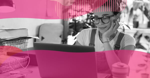 Mulher jovem de óculos trabalhando em home office no notebook, representando o início de um negócio online.