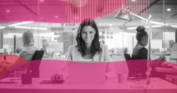 Mulher sorrindo enquanto trabalha em um notebook em um escritório moderno, representando estratégias de conteúdo audiovisual para captar clientes pela internet.