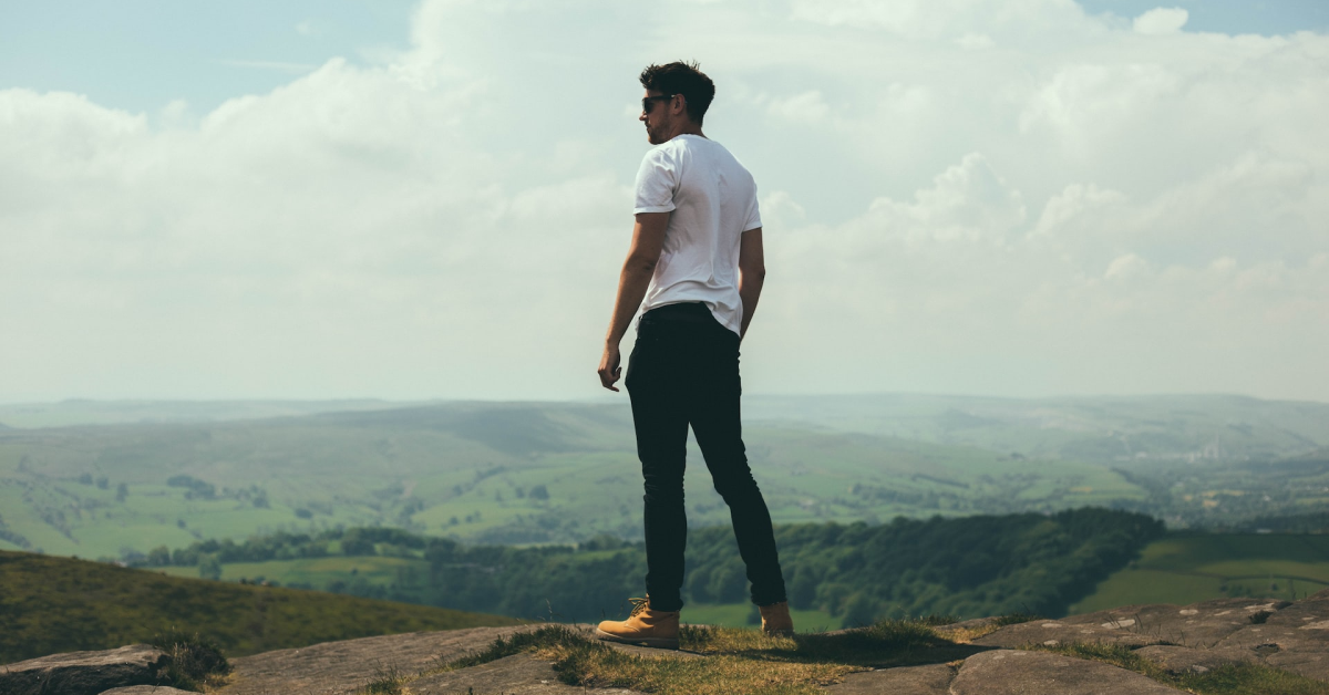 Moço olhando para o horizonte em uma montanha