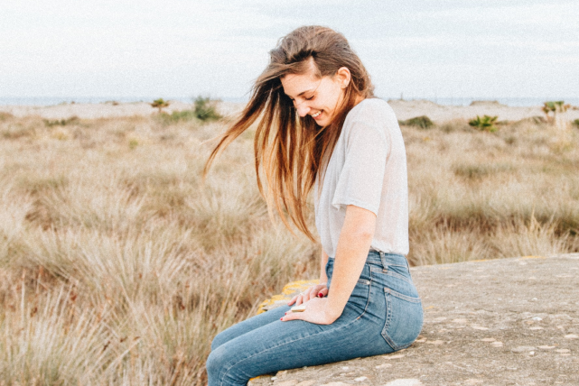 Moça sentada em uma pedra e sorrindo